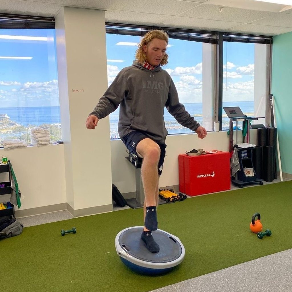 A man standing on an exercise ball in an office.